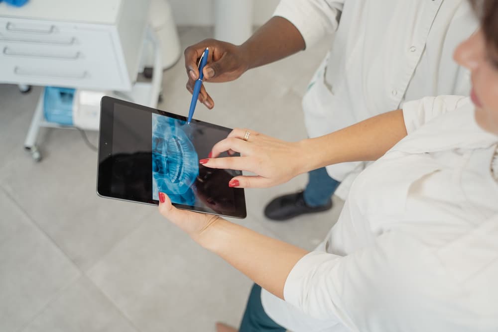 Dentista mostrando o raio-X no tablet para a paciente